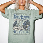 Bay color Comfort Colors 1717 relaxed fit t-shirt with gothic dark romance graphic — a raven perched on a skull, a snake coiled on stacked books, a candle, and florals, with the text "Dark Romance Book Club — Enter for the Plot, Stay for the Trauma"