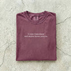 Berry Comfort Colors tee folded flat reading "I like romantasy and maybe three people." in a typewriter font.