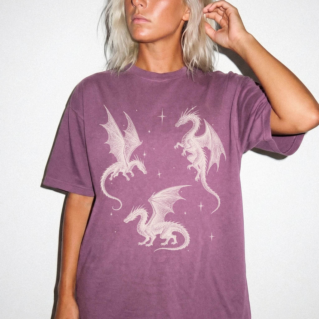 Berry color Comfort Colors 1717 relaxed fit t-shirt with whimsigoth fantasy graphic — three detailed dragon illustrations surrounded by stars and celestial details in off-white line art