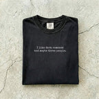 Black Comfort Colors tee folded flat reading "I like dark romance and maybe three people." in a minimalist typewriter font.