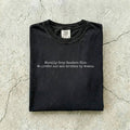 Black Comfort Colors tee folded flat on a concrete background reading "Morally grey readers club. We prefer our men written by women." in a minimal typewriter font.