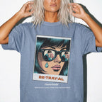 Blue Jean color Comfort Colors 1717 relaxed fit t-shirt with retro pop art graphic — a woman with teal hair and sunglasses reflecting a couple, a single tear on her cheek, with the word BE·TRAY·AL (betrayal) and the tagline "she loves a plot twist, but not this kind" 