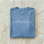 Blue Jean Comfort Colors tee folded flat on a concrete background reading "Morally grey readers club. We prefer our men written by women." in a minimal typewriter font.