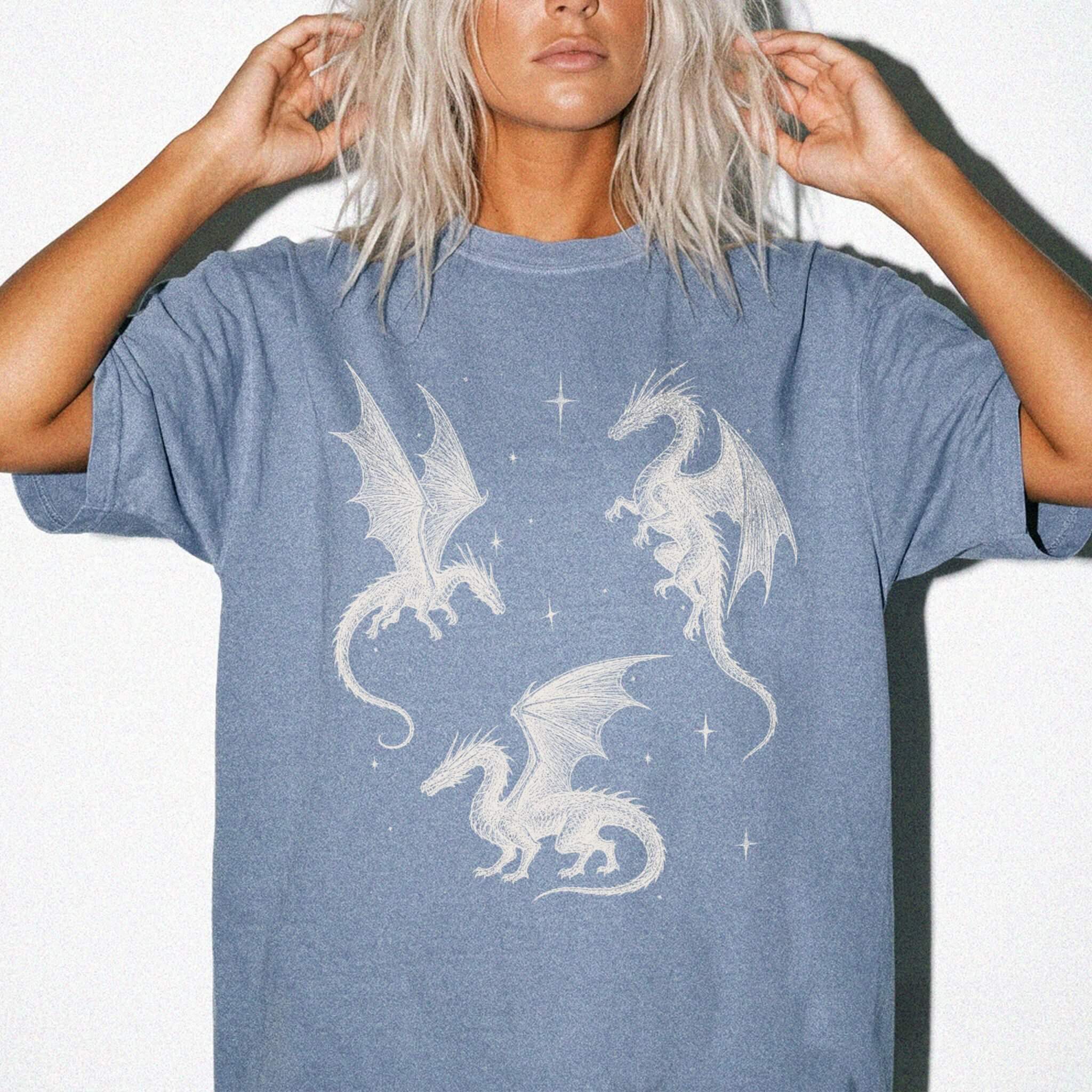 Blue Jean color Comfort Colors 1717 relaxed fit t-shirt with whimsigoth fantasy graphic — three detailed dragon illustrations surrounded by stars and celestial details in off-white line art