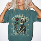Blue Spruce Comfort Colors 1717 relaxed fit t-shirt with dark romance graphic — a skeleton holding a red rose beneath an arch with the text "Morally Grey — My Favorite Color" and the tagline "He is mean to everyone except me"
