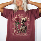 Brick color Comfort Colors 1717 relaxed fit t-shirt with dark romance graphic — a skeleton holding a red rose beneath an arch with the text "Morally Grey — My Favorite Color" and the tagline "He is mean to everyone except me"