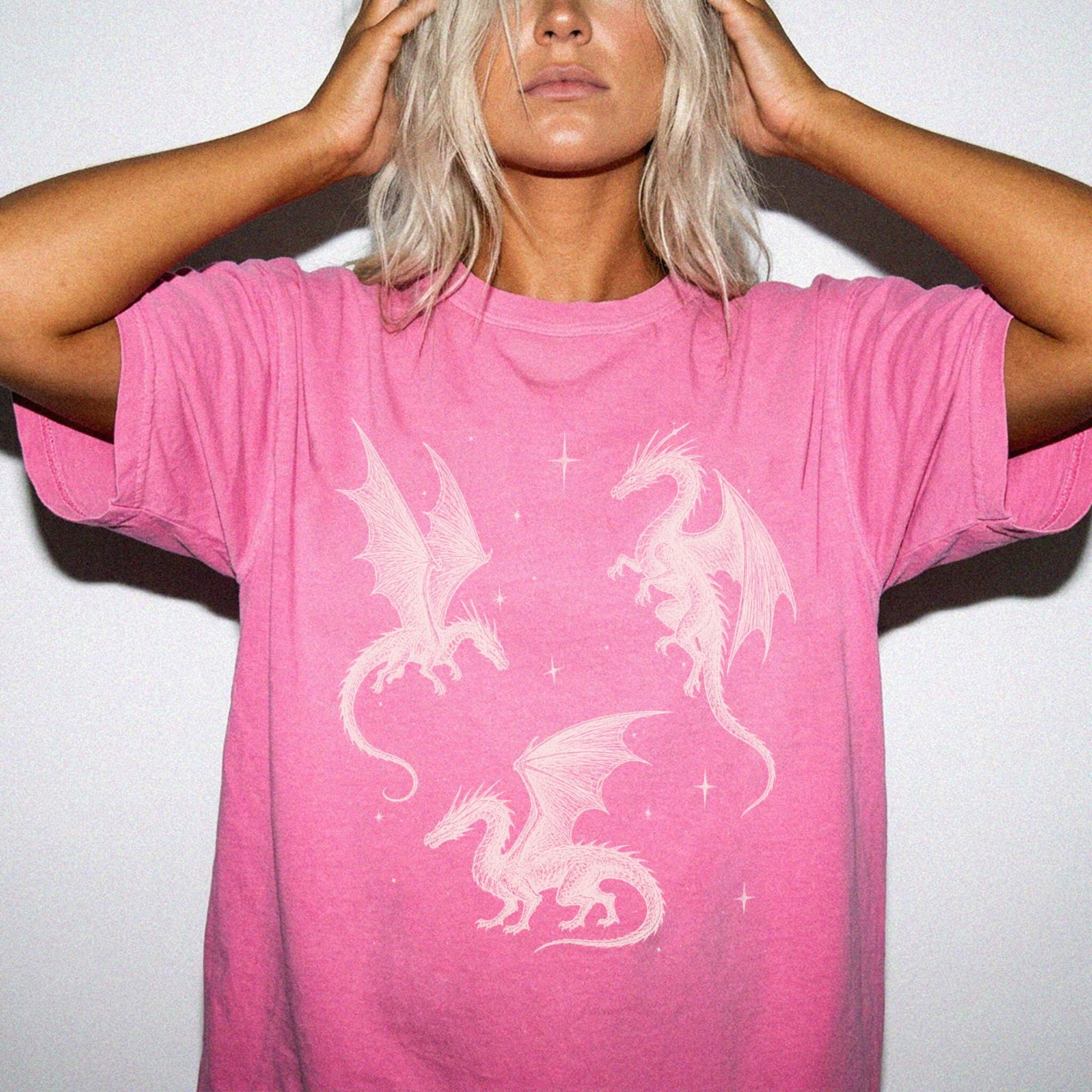 Crunchberry color Comfort Colors 1717 relaxed fit t-shirt with whimsigoth fantasy graphic — three detailed dragon illustrations surrounded by stars and celestial details in off-white line art