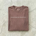 Espresso Comfort Colors tee folded flat on a concrete background reading "Enemies make the best lovers." in a minimal typewriter font.