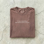 Espresso Comfort Colors tee folded flat reading "I like romantasy and maybe three people." in a typewriter font.