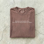 Espresso Comfort Colors tee folded flat on a concrete background reading "Morally grey readers club. We prefer our men written by women." in a minimal typewriter font.