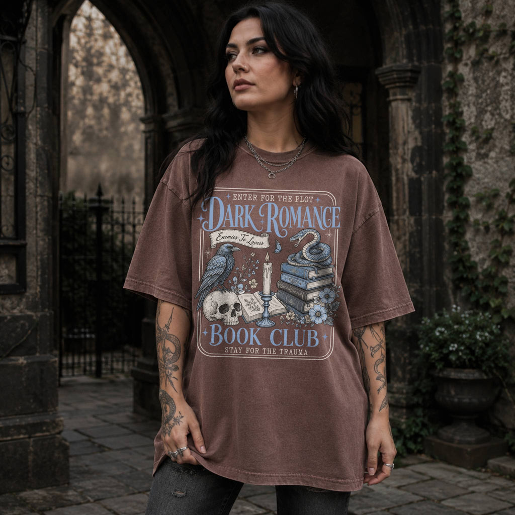 Espresso color Comfort Colors 1717 relaxed fit t-shirt with gothic dark romance graphic — a raven perched on a skull, a snake coiled on stacked books, a candle, and florals, with the text "Dark Romance Book Club — Enter for the Plot, Stay for the Trauma"