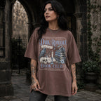Espresso color Comfort Colors 1717 relaxed fit t-shirt with gothic dark romance graphic — a raven perched on a skull, a snake coiled on stacked books, a candle, and florals, with the text "Dark Romance Book Club — Enter for the Plot, Stay for the Trauma"