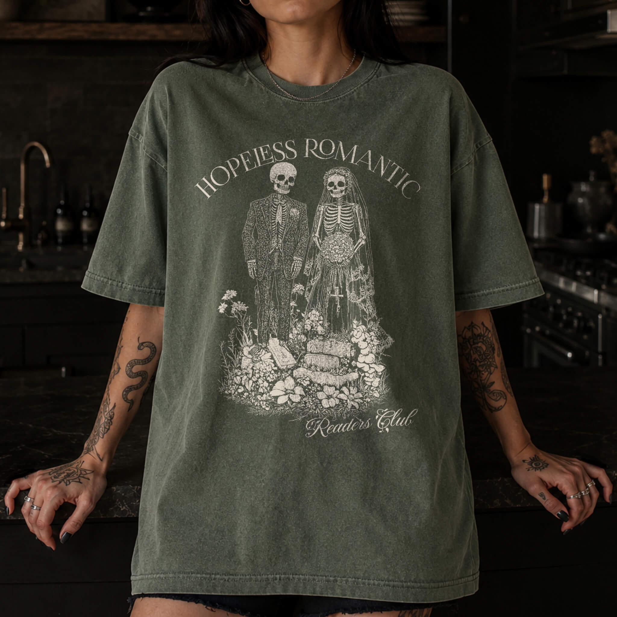 Hopeless Romantic Readers Club Tee in Moss – vintage-style Comfort Colors graphic tee for dark romance readers. Graphic features a skeleton couple on their wedding day.