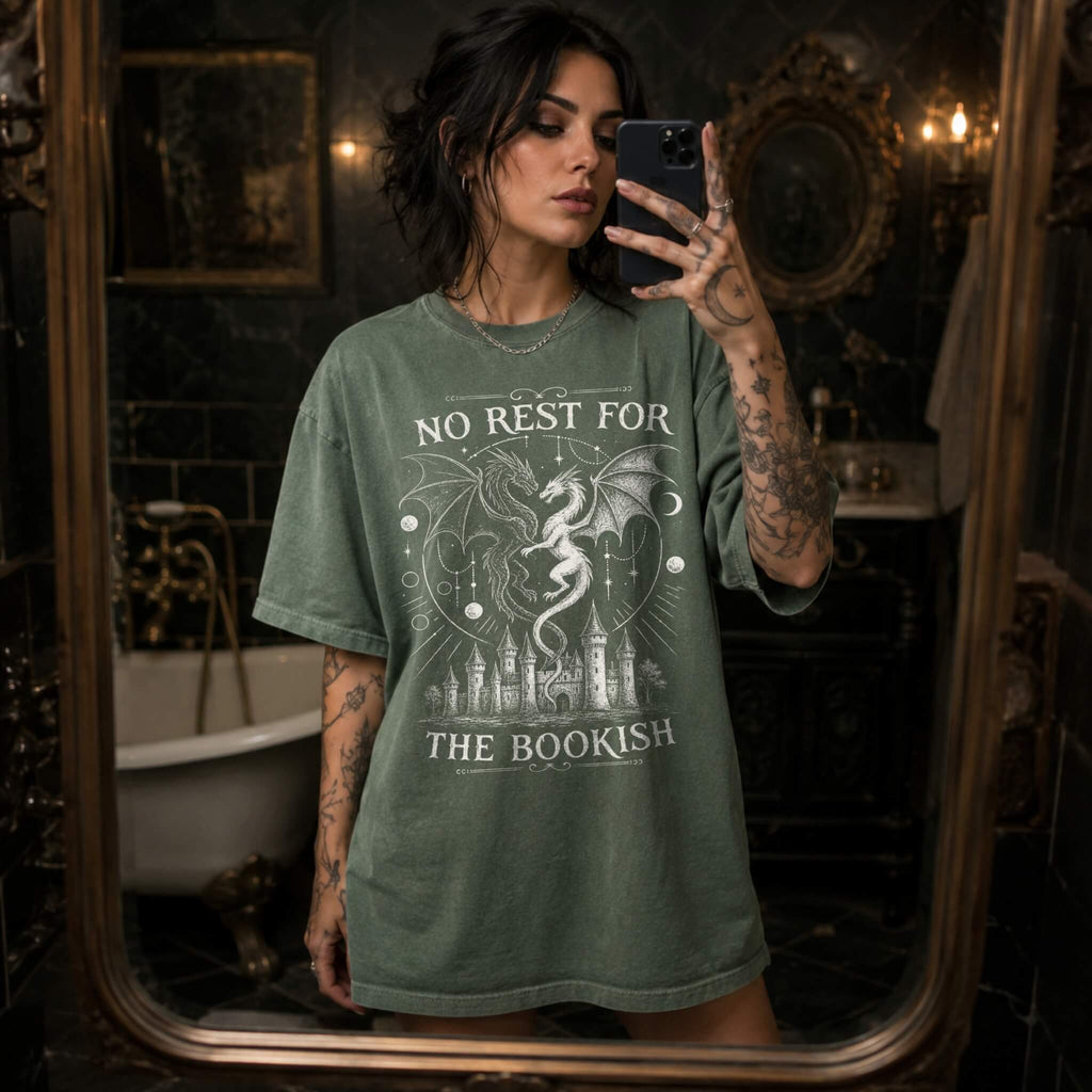 Moss color Comfort Colors 1717 relaxed fit t-shirt with gothic romantasy graphic — two dragons soaring over a castle beneath moons and celestial details, with the text "No Rest for the Bookish"