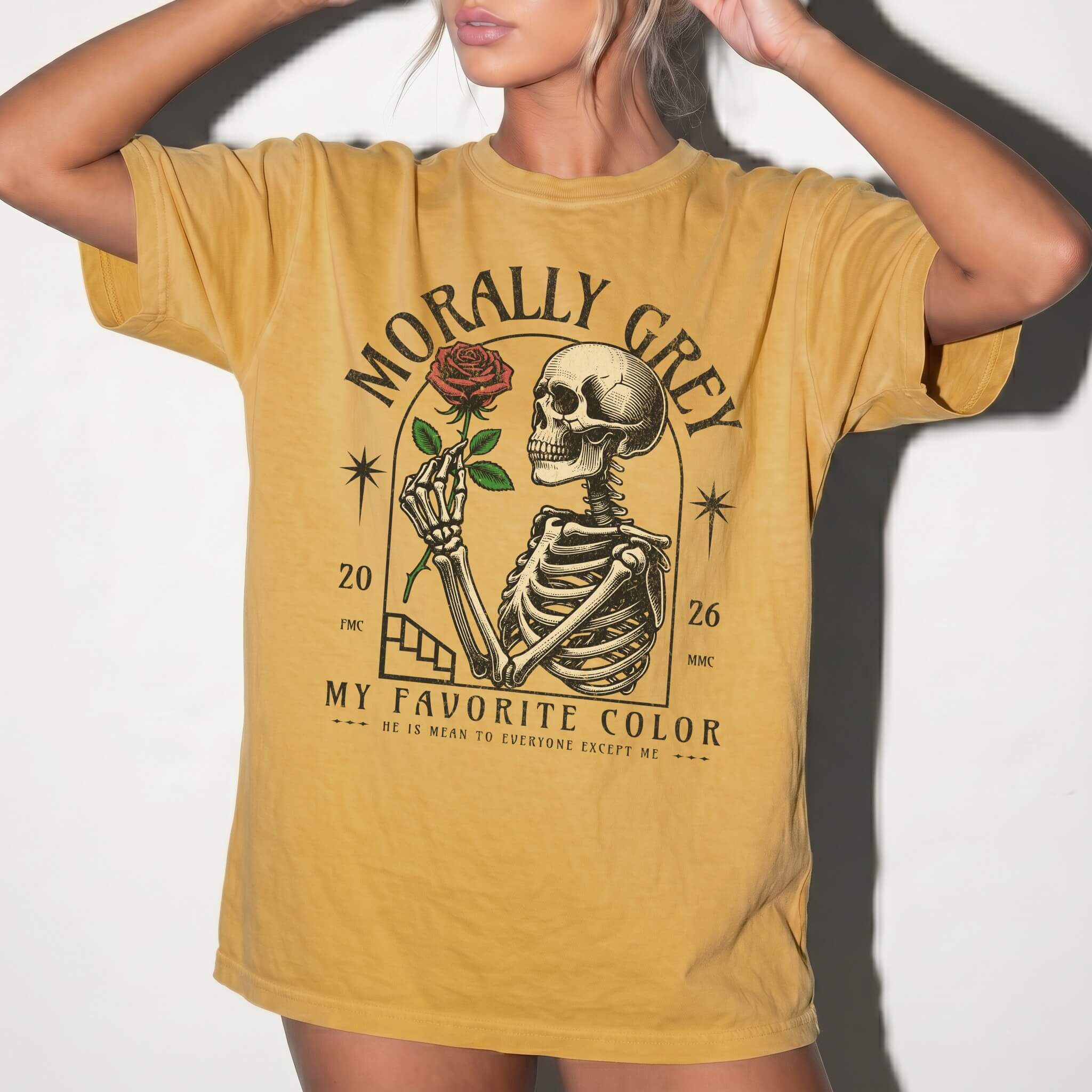 Mustard color Comfort Colors 1717 relaxed fit t-shirt with dark romance graphic — a skeleton holding a red rose beneath an arch with the text "Morally Grey — My Favorite Color" and the tagline "He is mean to everyone except me"