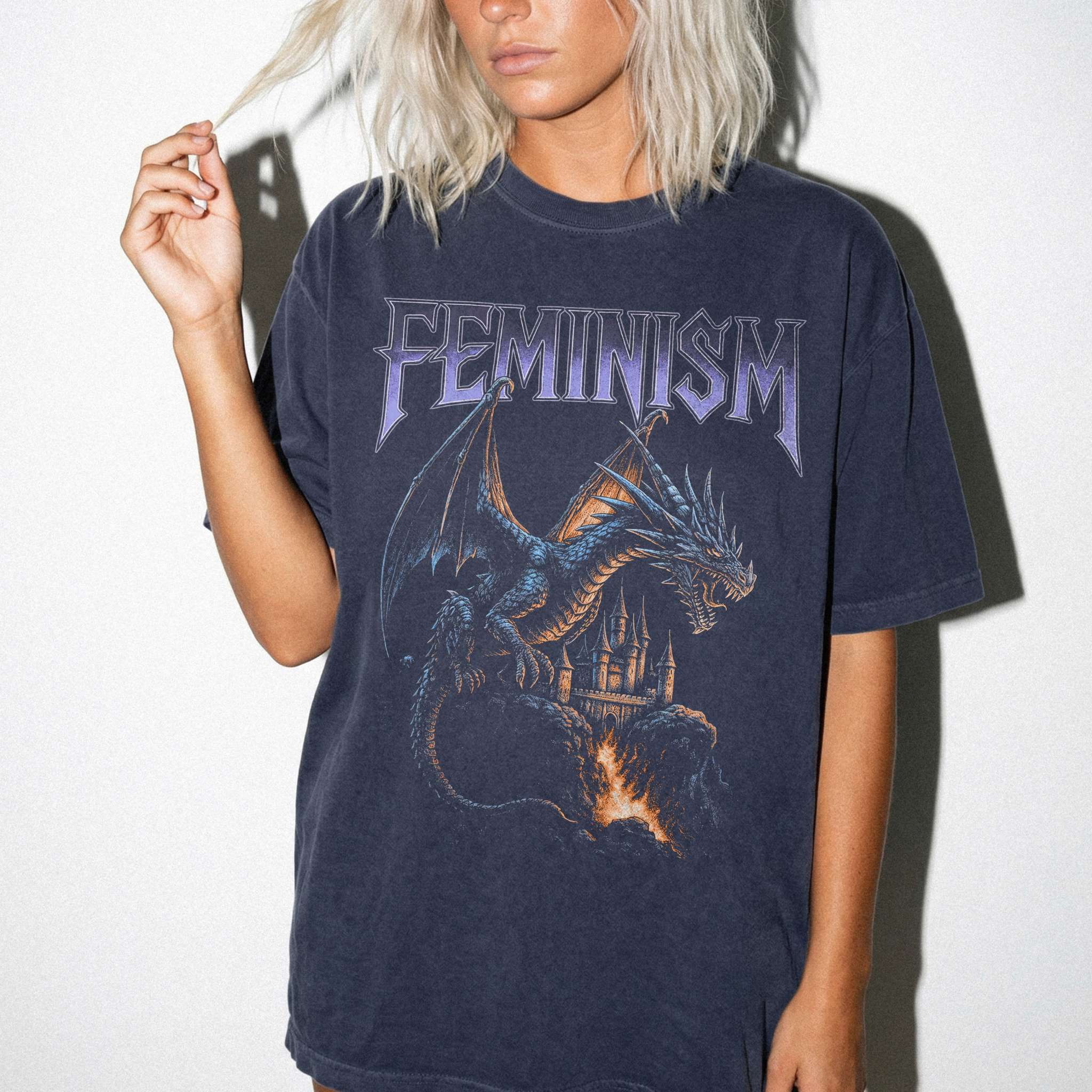 Woman wearing navy Comfort Colors relaxed tee with Feminism vintage metal graphic — dragon and lava-flowing castle design