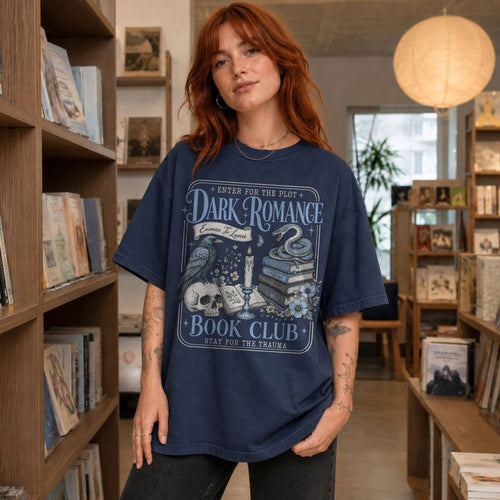 Navy color Comfort Colors 1717 relaxed fit t-shirt with gothic dark romance graphic — a raven perched on a skull, a snake coiled on stacked books, a candle, and florals, with the text "Dark Romance Book Club — Enter for the Plot, Stay for the Trauma"