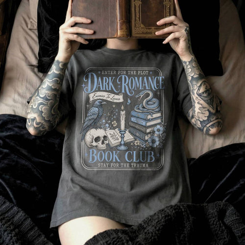 Pepper color Comfort Colors 1717 relaxed fit t-shirt with gothic dark romance graphic — a raven perched on a skull, a snake coiled on stacked books, a candle, and florals, with the text "Dark Romance Book Club — Enter for the Plot, Stay for the Trauma"