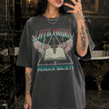 Mirror selfie of woman wearing pepper Comfort Colors relaxed tee with Late Night Reader Society vintage metal graphic — winged open book and dagger design