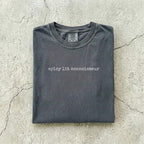 Pepper Comfort Colors tee folded flat on a concrete background reading "spicy lit connoisseur" in a minimal typewriter font.