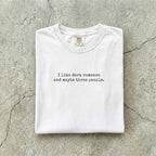 White Comfort Colors tee folded flat reading "I like dark romance and maybe three people." in a minimalist typewriter font.