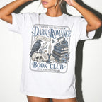 White color Comfort Colors 1717 relaxed fit t-shirt with gothic dark romance graphic — a raven perched on a skull, a snake coiled on stacked books, a candle, and florals, with the text "Dark Romance Book Club — Enter for the Plot, Stay for the Trauma"